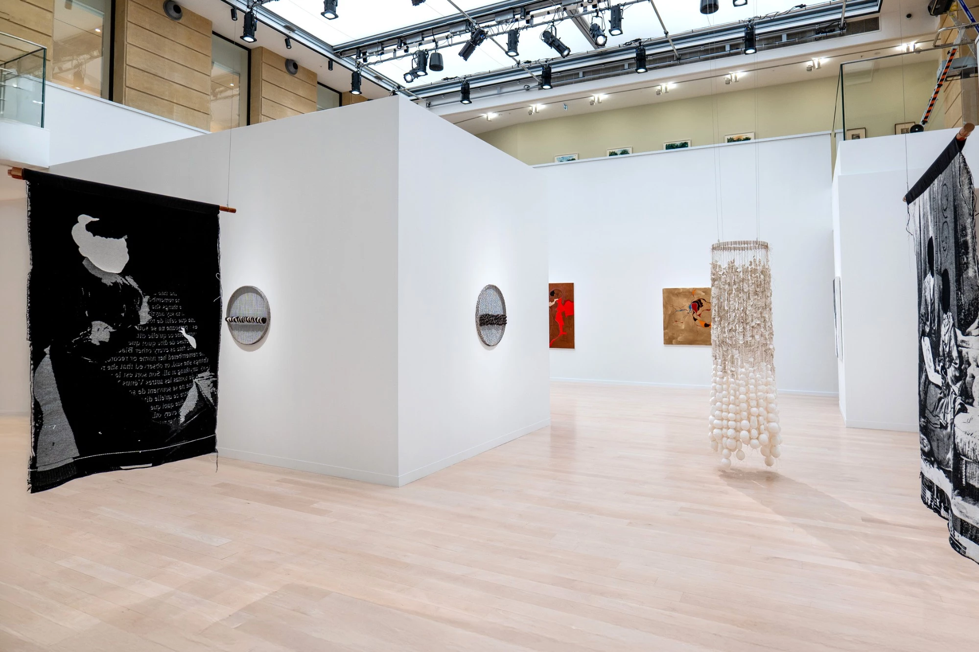 Ausstellung im Canadian Cultural Centre in Paris: frei stehende weiße Mila-wall Wandblöcke unter einem Glasdach, davor hängende Textilarbeiten und eine Skulptur